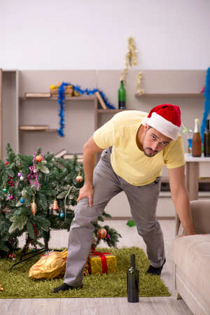 Young man cleaning the apartment after Christmas partyの写真素材