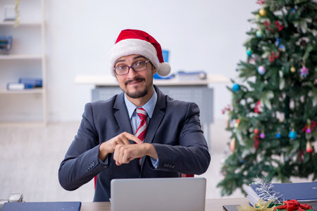 Young male employee celebrating Christmas at workplaceの写真素材