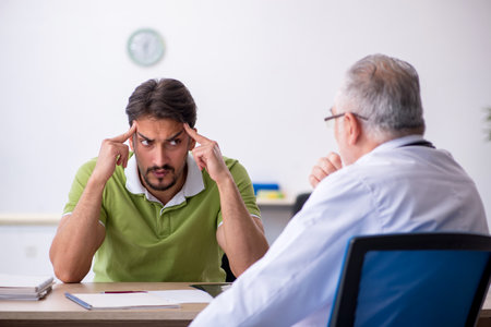 Young man visiting old male doctorの写真素材
