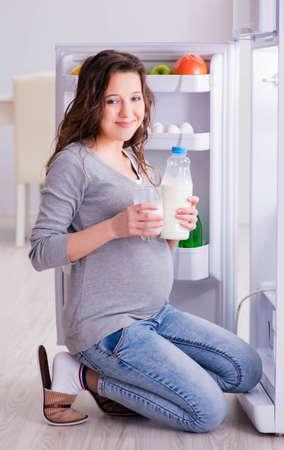 Pregnant woman near fridge looking for food and snacksの写真素材