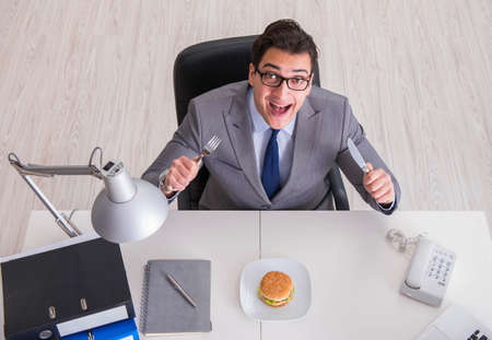 Hungry funny businessman eating junk food sandwichの写真素材