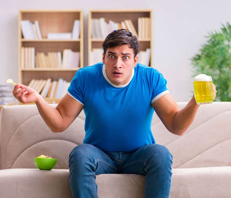 Man watching football at home sitting in couchの写真素材
