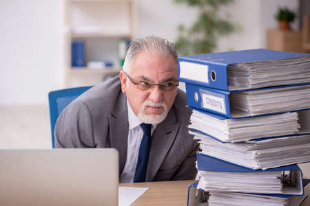 Old male employee unhappy with excessive work in the officeの写真素材