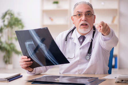 Old male doctor radiologist working in the clinic during pandemiの写真素材