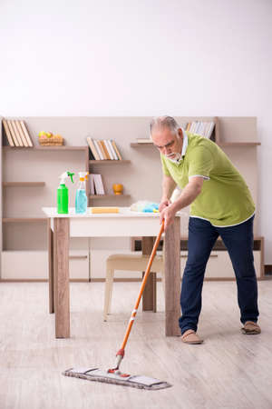 Old man cleaning the houseの写真素材
