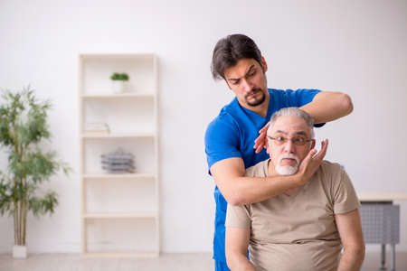 Old male patient visting young male doctor chiropractorの写真素材