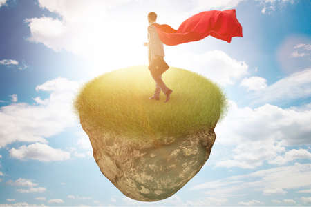 Businessman superhero on floating island in business conceptの写真素材