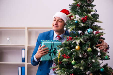Young male employee celebrating Christmas at workplaceの写真素材