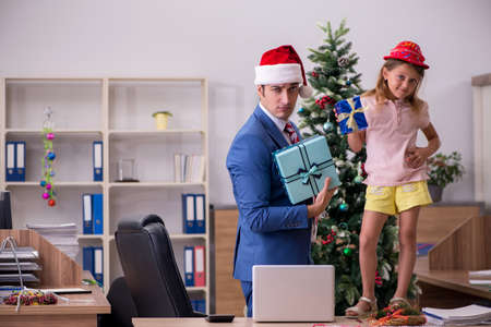 Young male employee celebrating Christmas at workplace with hisの写真素材