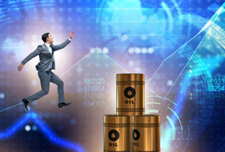 Businessman jumping from stack of oil barrels