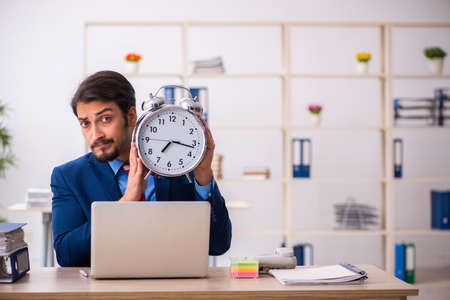 Young male employee in time management conceptの写真素材