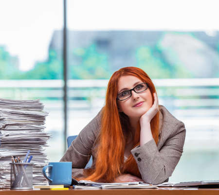 Stressed businesswoman with stack of papersの写真素材