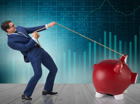Businessman pulling piggybank with ropeの写真素材