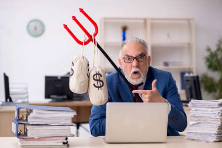 Old male employee unhappy with excessive work in the officeの写真素材