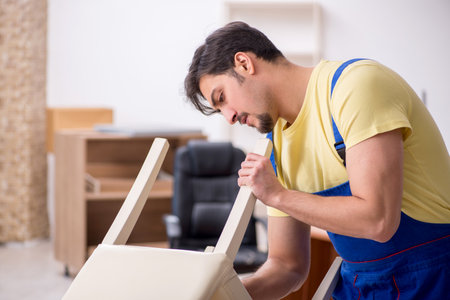 Young male carpenter repairing chair in the officeの写真素材