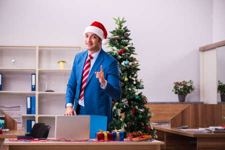 Young male employee celebrating Christmas at workplaceの写真素材