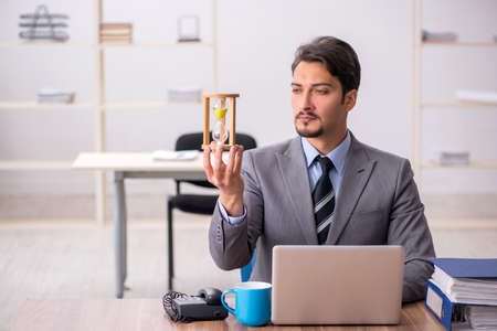 Young male employee in time management conceptの写真素材
