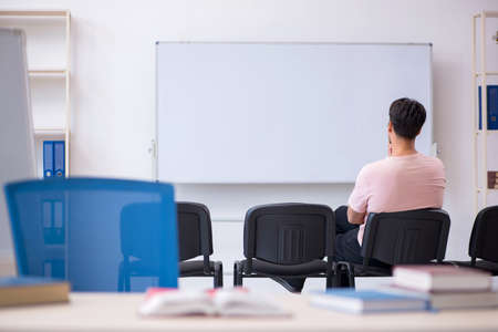 Young male teacher in the classroom during pandemicの写真素材