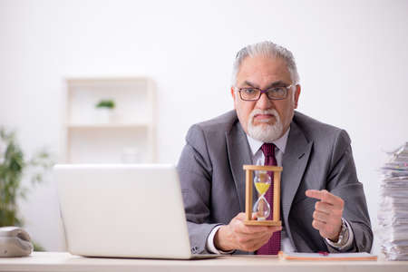Old male employee in time management concept