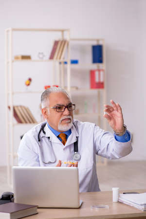 Old male doctor working in the clinicの写真素材