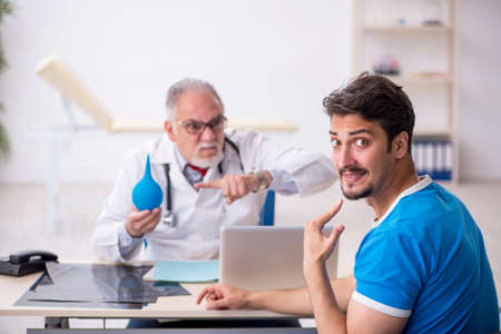 Young male patient visiting old male doctor gastroenterologistの写真素材