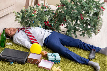 Young handsome employee celebrating Christmas at workplaceの写真素材