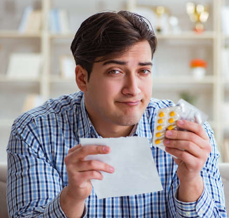 Young man sitting on the sofa with pills and prescriptionの写真素材