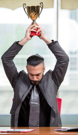 Businessman with winners cup trophy in business conceptの写真素材