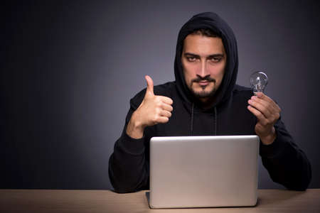 Young male hacker on grey background