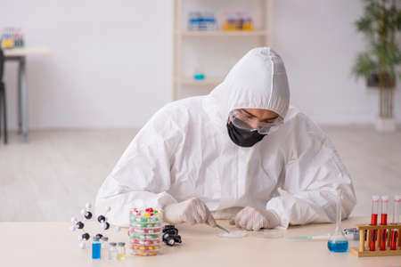 Young male chemist in drugs synthesis conceptの写真素材