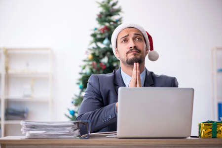 Young male employee celebrating Christmas at workplaceの写真素材
