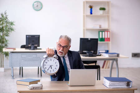 Old male employee in time management conceptの写真素材