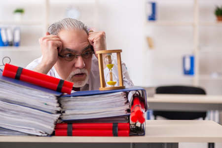 Old male employee with dynamite in the officeの写真素材