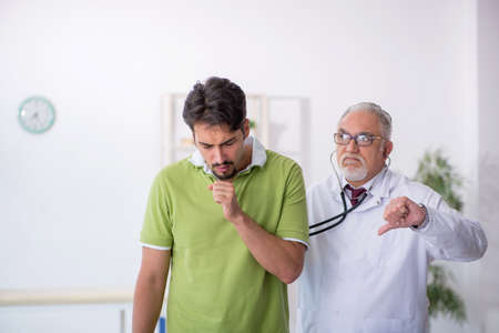 Young male patient visiting old male doctorの写真素材