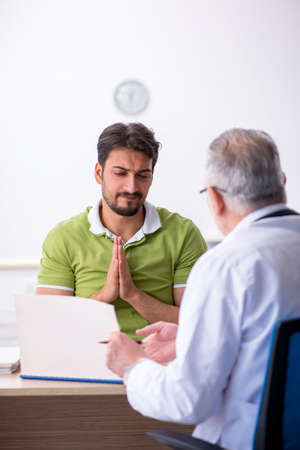 Young man visiting old male doctorの写真素材