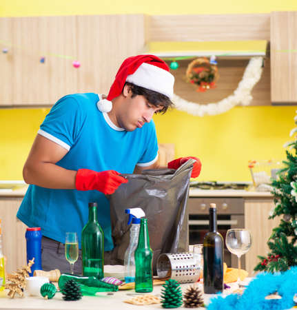Young man cleaning kitchen after Christmas partyの写真素材