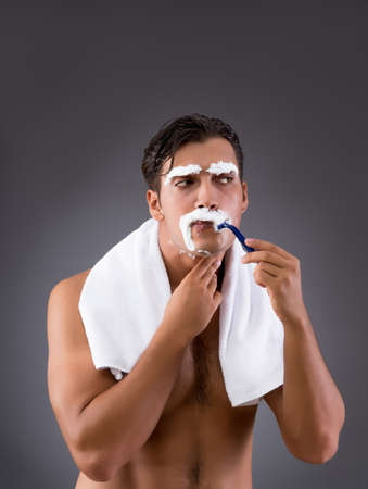 Handsome man shaving against dark backgroundの写真素材