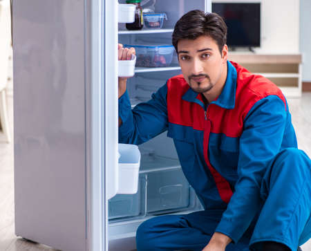 Professional contractor repairing broken fridgeの写真素材