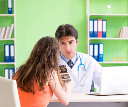 Pregnant woman visiting male gynecologyst at the clinicの写真素材