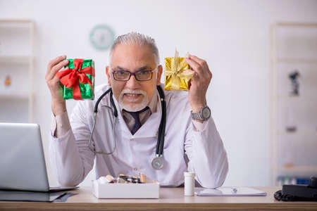 Old male doctor celebrating Christmas at the hospitalの写真素材
