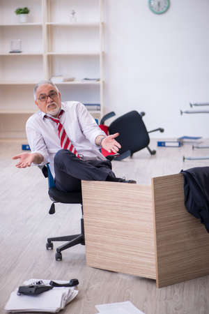 Old male employee working overtime in the officeの写真素材