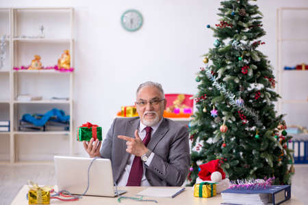 Aged male employee celebrating Christmas at workplaceの写真素材