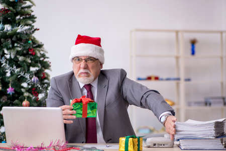 Aged male employee celebrating Christmas at workplaceの写真素材