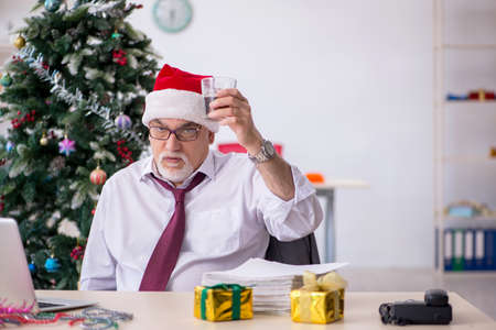 Aged male employee celebrating Christmas at workplaceの写真素材