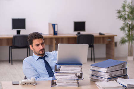 Young male employee and too much work in the office