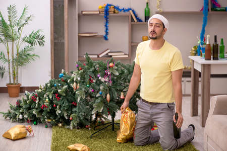 Young man cleaning the apartment after Christmas partyの写真素材