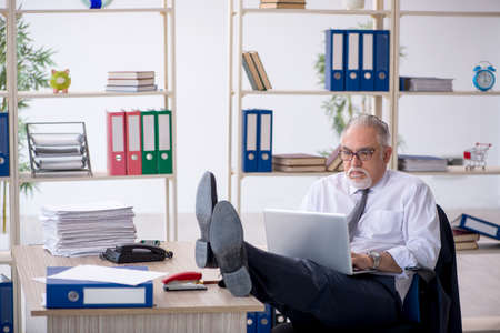 Old male employee and too much work in the officeの写真素材