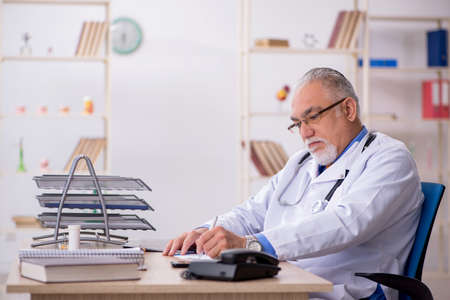 Old male doctor working in the clinicの写真素材