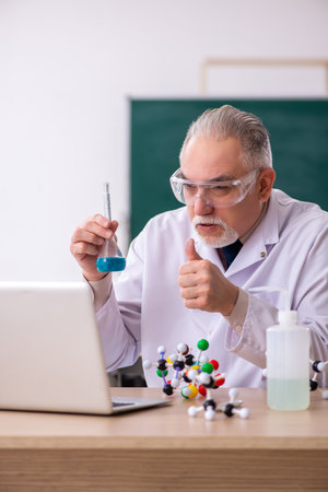 Old male teacher chemist in the classroomの写真素材