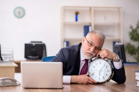 Old male employee in time management conceptの写真素材